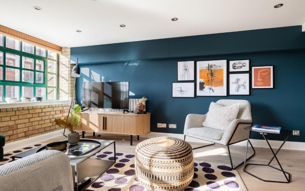 a living room with blue walls and two chairs and a table at The Wapping Wharf - Modern & Bright 2BDR Flat on the Thames with Parking in London