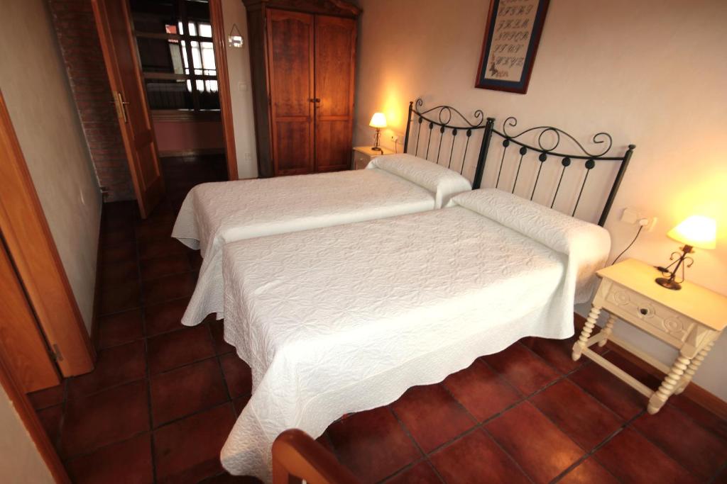 a bedroom with two beds and a table with two lamps at Casa Rural El Meson in Briones