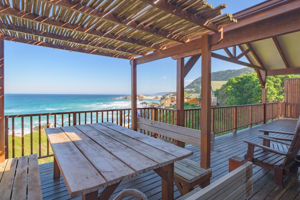 a wooden deck with a table and benches on the beach at Shick-Shack in Eersterivierstrand