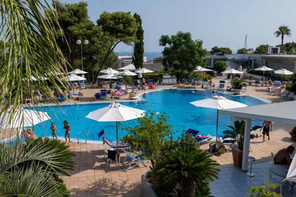 a large swimming pool with people sitting in chairs and umbrellas at Hotel Santa Lucia in Santa Cesarea Terme