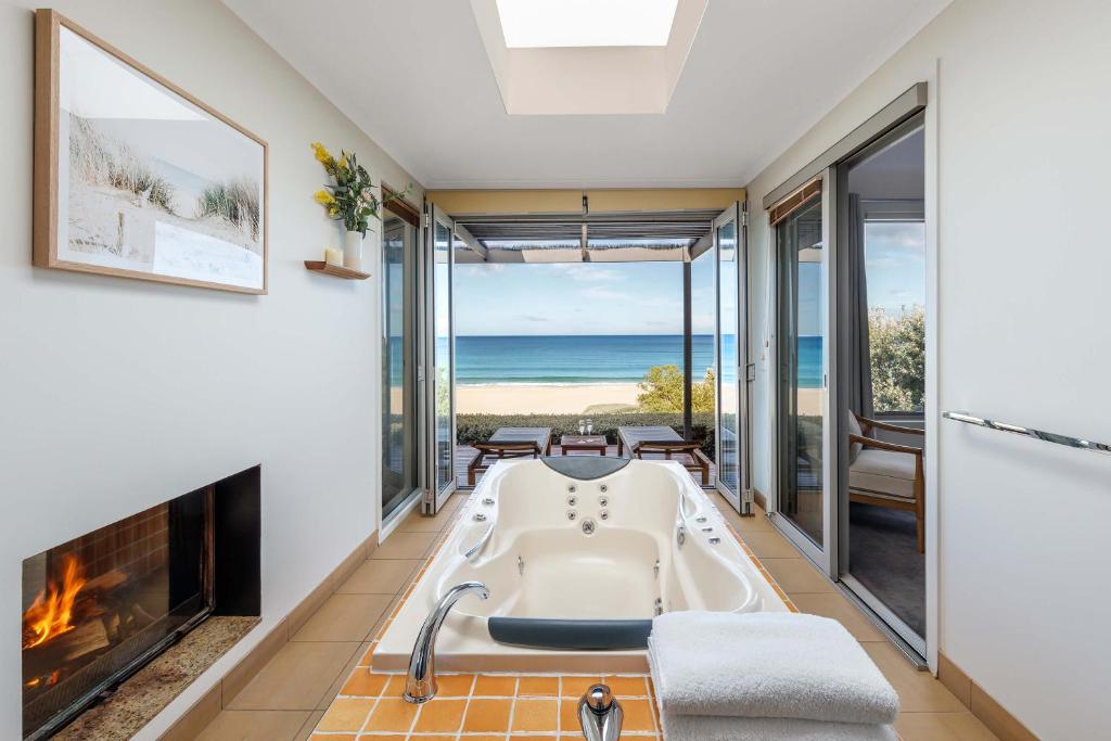 a bath tub in a room with a fireplace at Chocolate Gannets in Apollo Bay