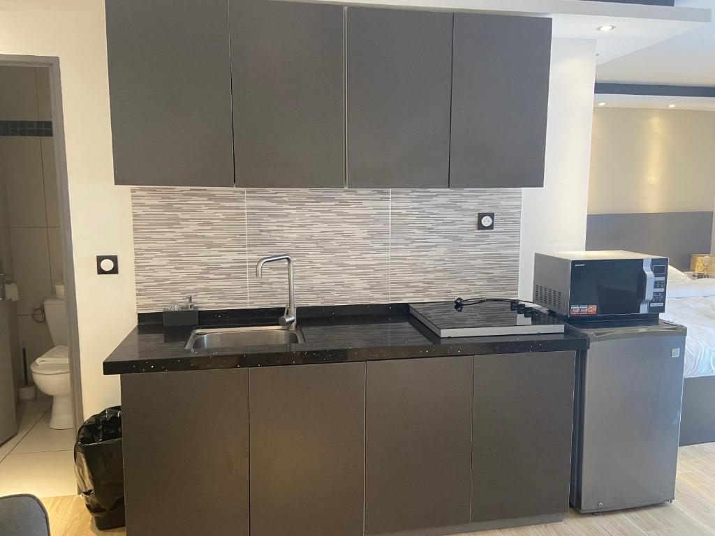 a kitchen with a sink and a microwave at Hôtel Select - Réunion in Saint-Denis