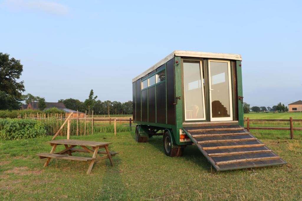 a green trailer with a wooden ramp and a picnic table at Slapen tussen de paarden in Essen