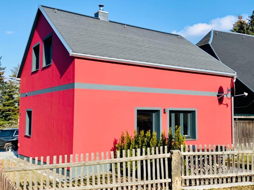 une maison rouge avec une clôture devant elle dans l'établissement Ferienhaus Papstdorf, à Gohrisch