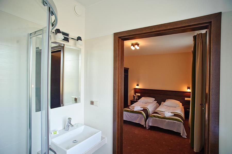 łazienka z 2 łóżkami, umywalką i lustrem w obiekcie Zajazd na Towarowej w mieście Dęblin