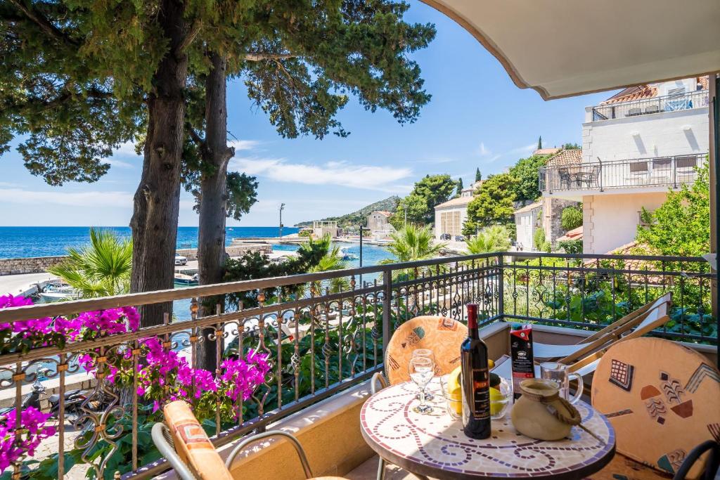 een tafel met wijnflessen op een balkon met uitzicht op de oceaan bij Apartments Villa Palma in Mlini