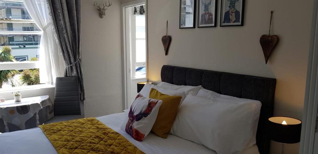 a bedroom with a bed with white pillows and a window at Newburgh Guesthouse in Torquay