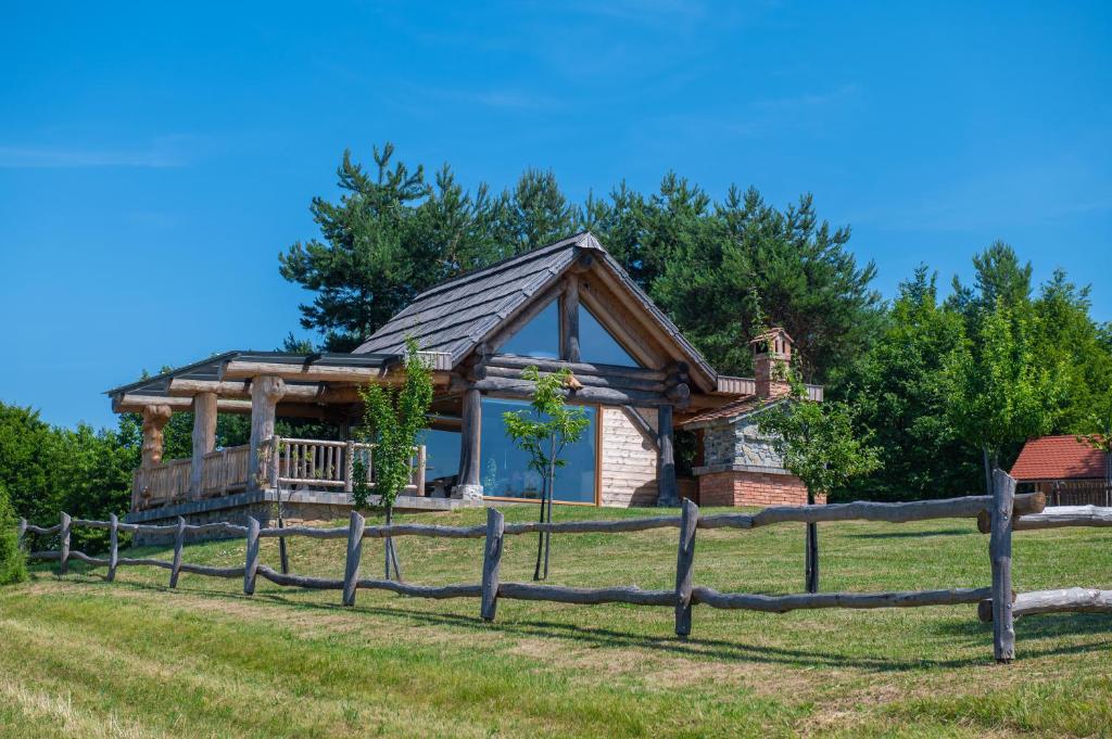 una cabaña de madera con una valla delante en Holiday Home Ernest Železni with hot tub, en Ivančna Gorica