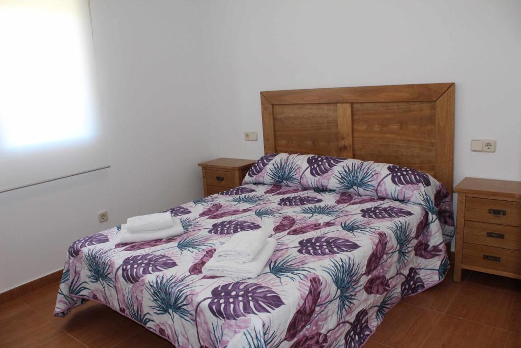 a bedroom with a bed and a wooden headboard at Casa Rural La Sureña 2 in Ossa de Montiel