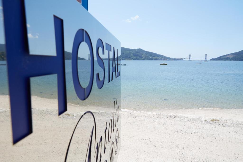 um sinal numa praia com o oceano ao fundo em Hostal Antolín em Redondela