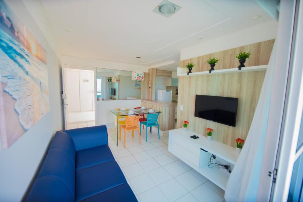 ein Wohnzimmer mit einem blauen Sofa und einer Küche in der Unterkunft Apartamento Encantador Verano na Praia in Natal