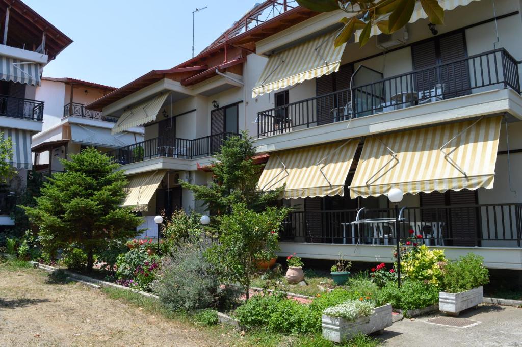 un edificio de apartamentos con balcones, árboles y plantas en Manos Kritikakis Apartments, en Platamonas