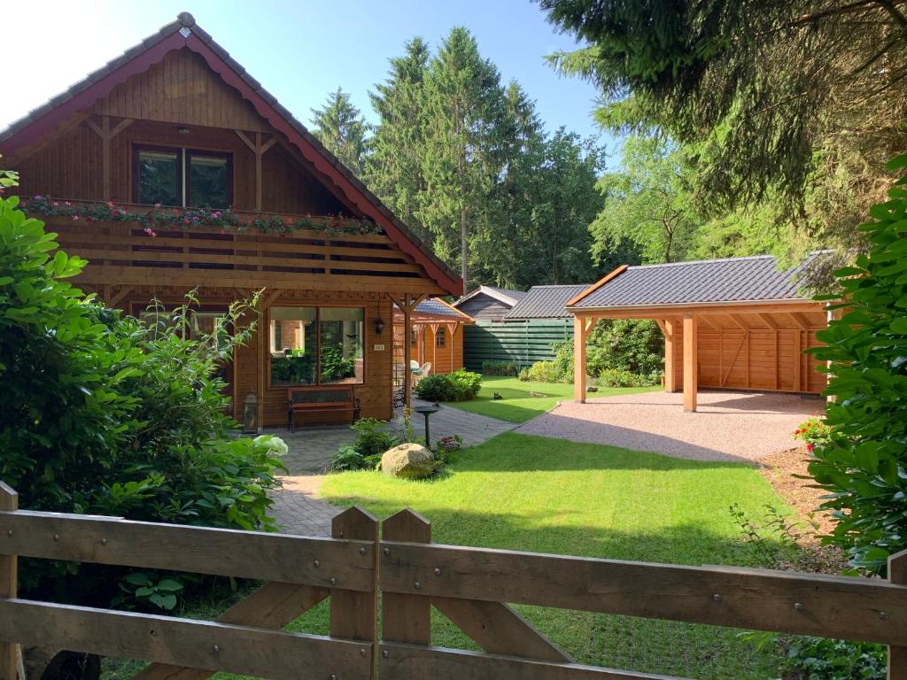 a wooden house with a fence and a yard at 't Holten Huus - Puur genieten in het bos. in Norg