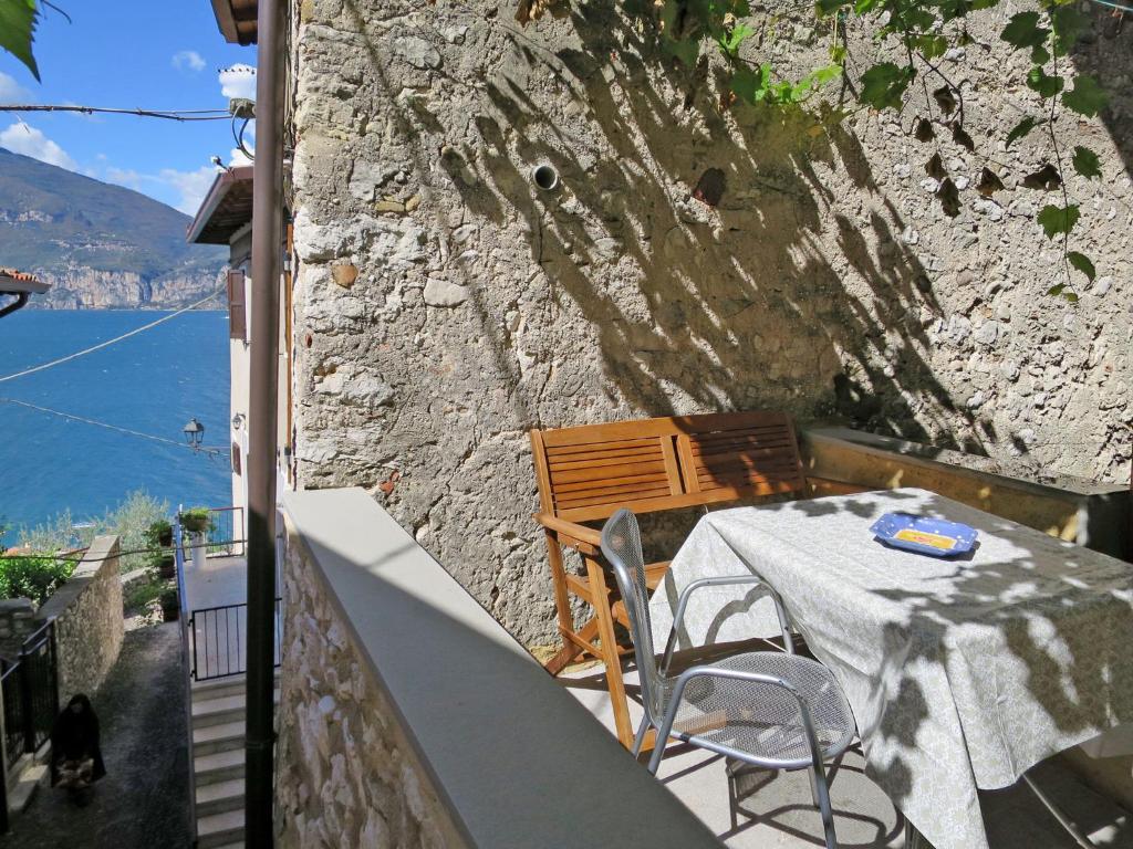 een tafel en stoelen op een balkon met een stenen muur bij Apartment Casa Vigna by Interhome in Sommavilla