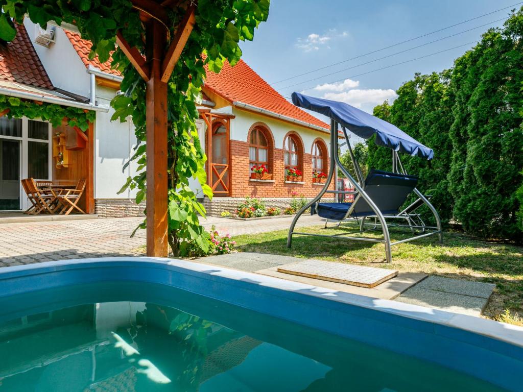 a pool in front of a house with a chair and umbrella at Apartment Swing by Interhome in Balatonszárszó