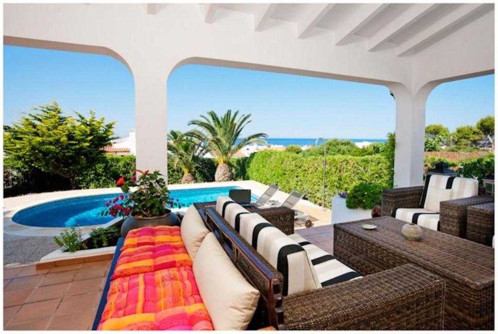patio con sofá y sillas y piscina en BINI CEL for 6 pax Heated Pool on request en Binibeca