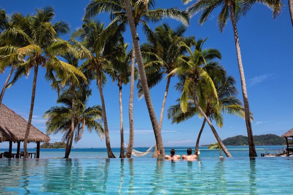 un gruppo di persone in una piscina a sfioro con palme di Tropica Island Resort-Adults Only a Malolo