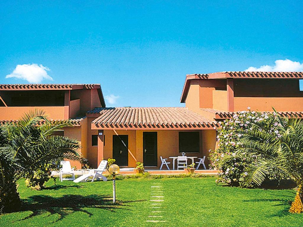 ein Haus mit einem Hof mit einer Terrasse und einem Haus in der Unterkunft Apartment Reale Marina - REI207 by Interhome in Costa Rei