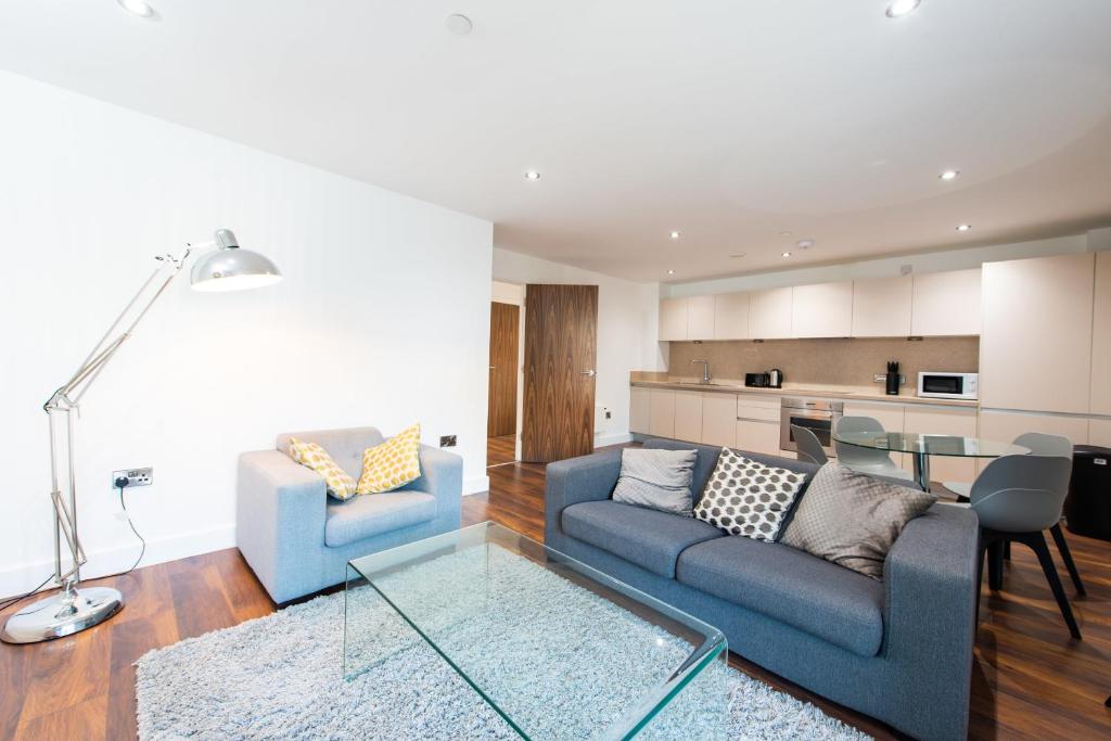 a living room with two blue couches and a table at Modern City Living Apartments at The Assembly Manchester in Manchester