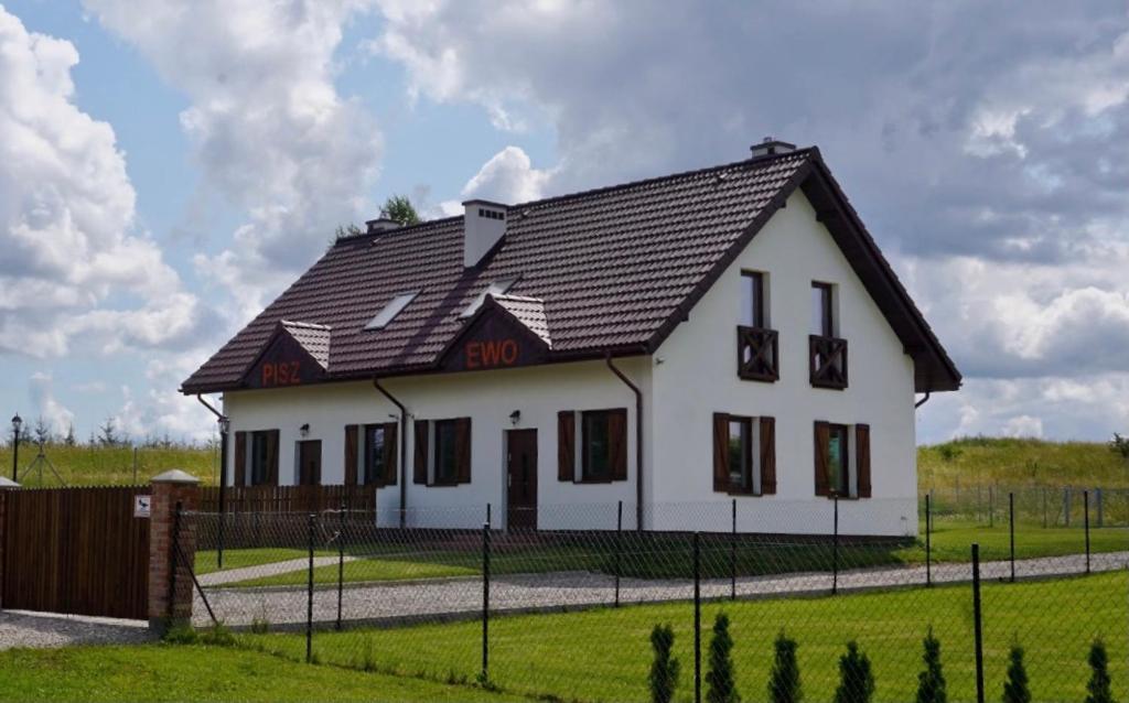 a white house with a black roof at Całoroczne domki nad jeziorem Luterskim in Piszewo
