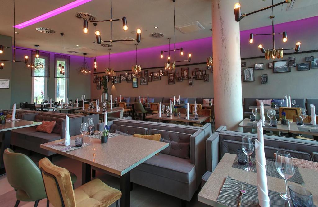 a restaurant with tables and chairs and purple lighting at Leonardo Hotel Dortmund in Dortmund