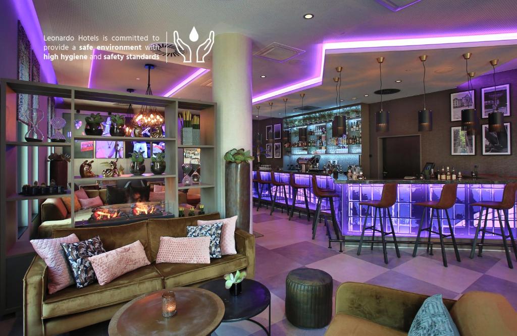a bar in a restaurant with purple lighting at Leonardo Hotel Dortmund in Dortmund