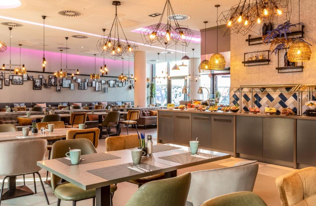a restaurant with tables and chairs and a bar at Leonardo Hotel Dortmund in Dortmund