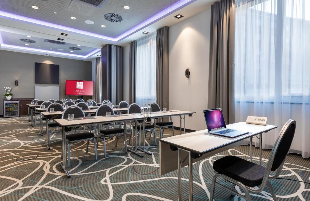 a conference room with tables and chairs and a laptop at Leonardo Hotel Dortmund in Dortmund