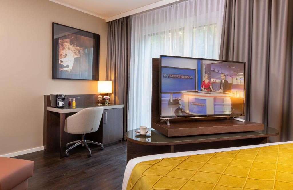 a hotel room with a television and a bed at Leonardo Hotel Dortmund in Dortmund