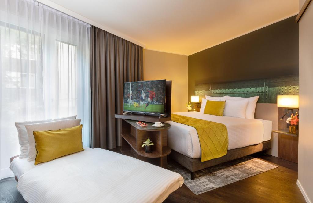 a hotel room with two beds and a flat screen tv at Leonardo Hotel Dortmund in Dortmund