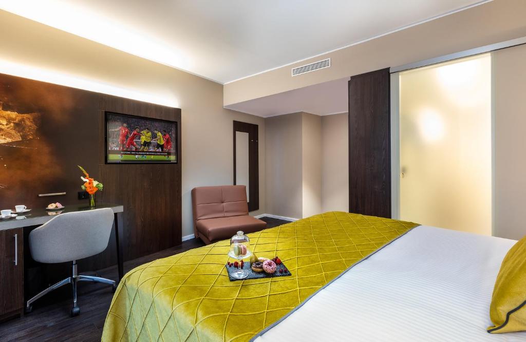 a hotel room with a bed and a desk and a chair at Leonardo Hotel Dortmund in Dortmund
