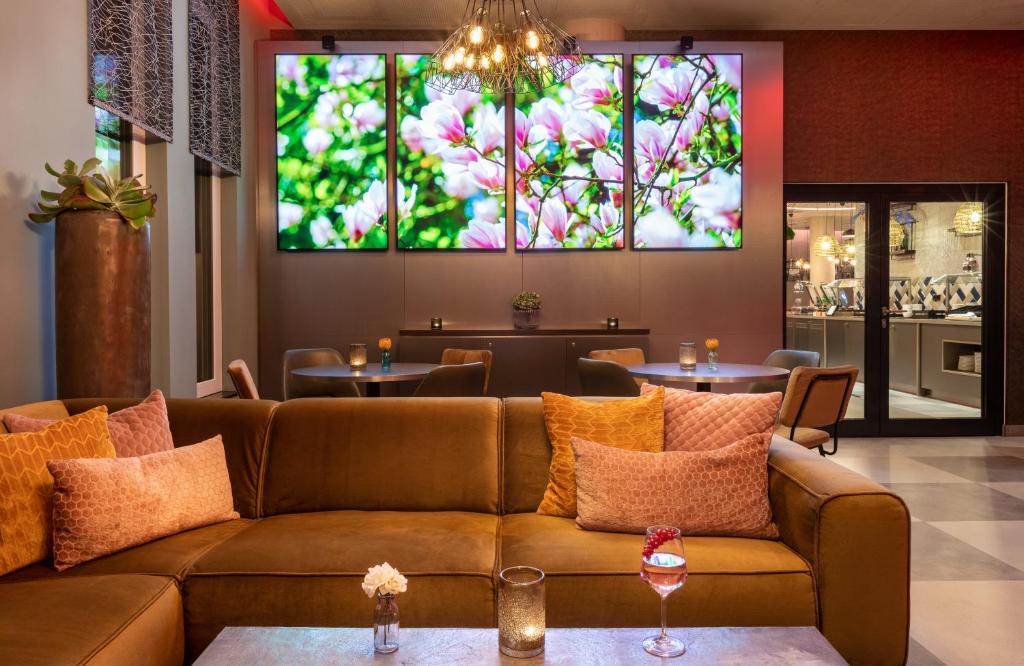 a living room with a couch and tables at Leonardo Hotel Dortmund in Dortmund