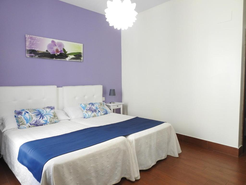 um quarto com uma cama branca e lençóis azuis em Habitaciones Amelia em Alicante