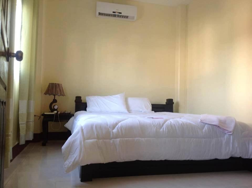 a bedroom with a large white bed and a lamp at Apartment Thidathip in Vientiane