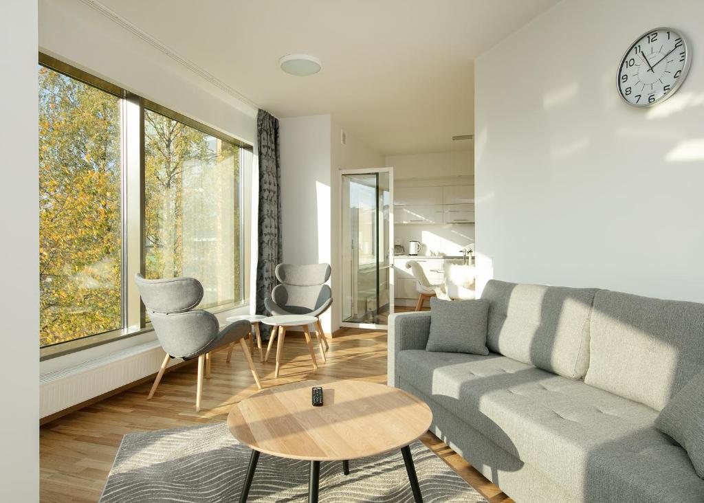 a living room with a couch and chairs and a clock at Cozy Lootsi Residence with Sauna and Balcony - Tallinn city centre in Tallinn