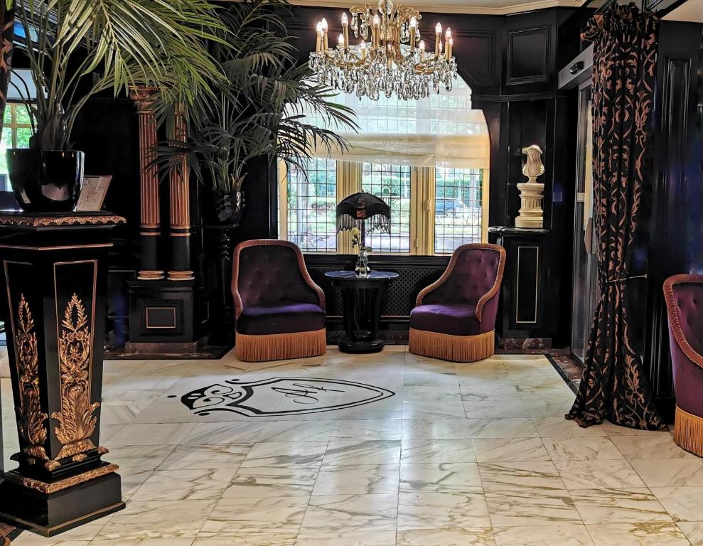 a lobby with chairs and a table and a chandelier at Apollofirst Boutique Hotel in Amsterdam