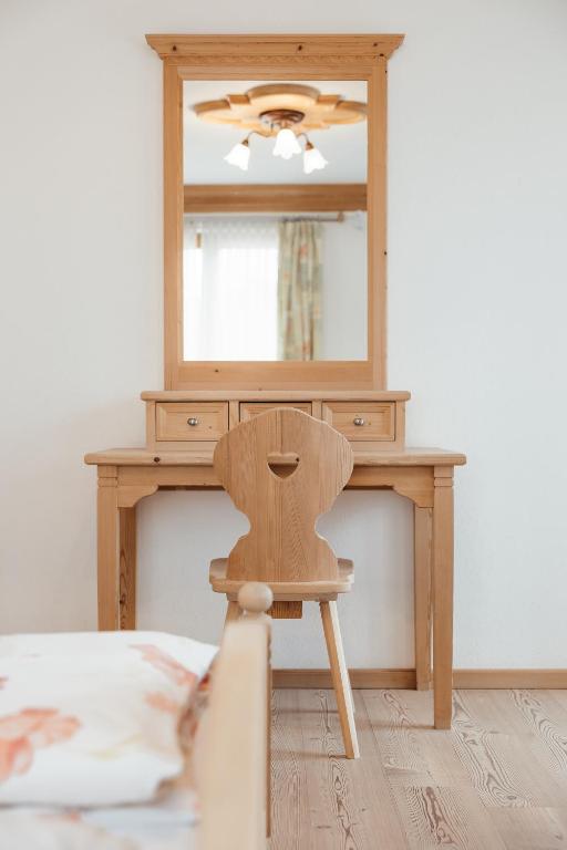 a wooden chair in front of a dressing table with a mirror at Garni Ciasa Urban in Badia