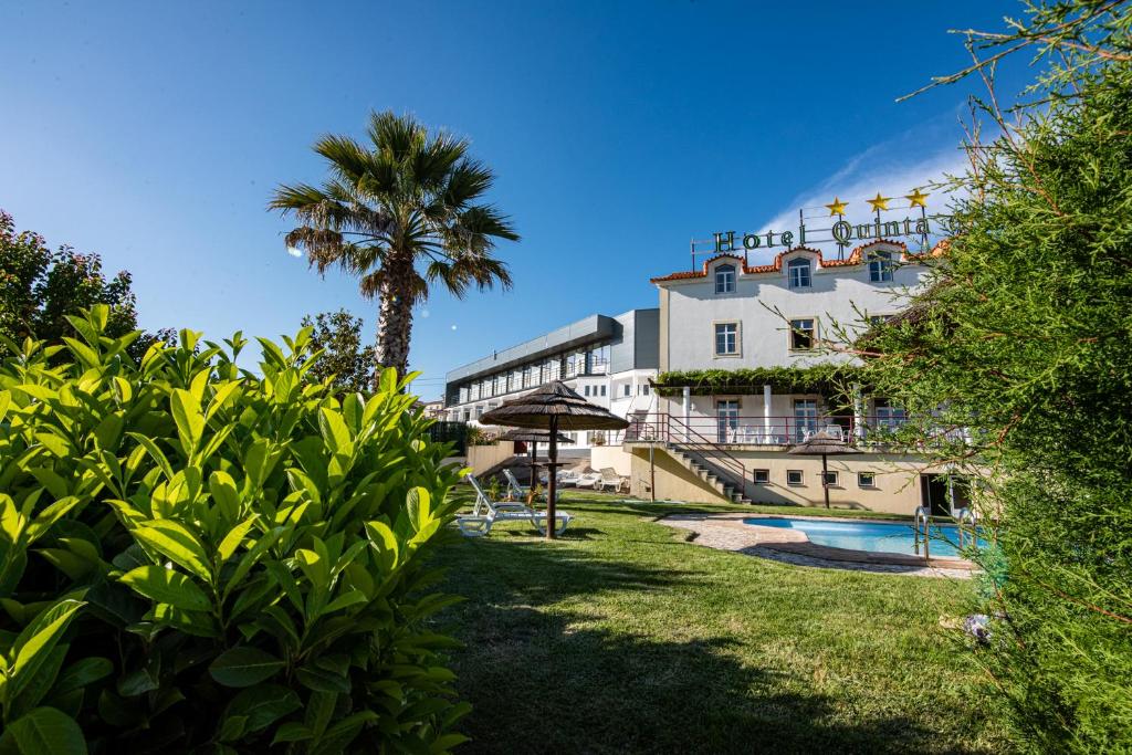 un edificio con una palmera y una piscina en Hotel Quinta do Viso en Miranda do Corvo