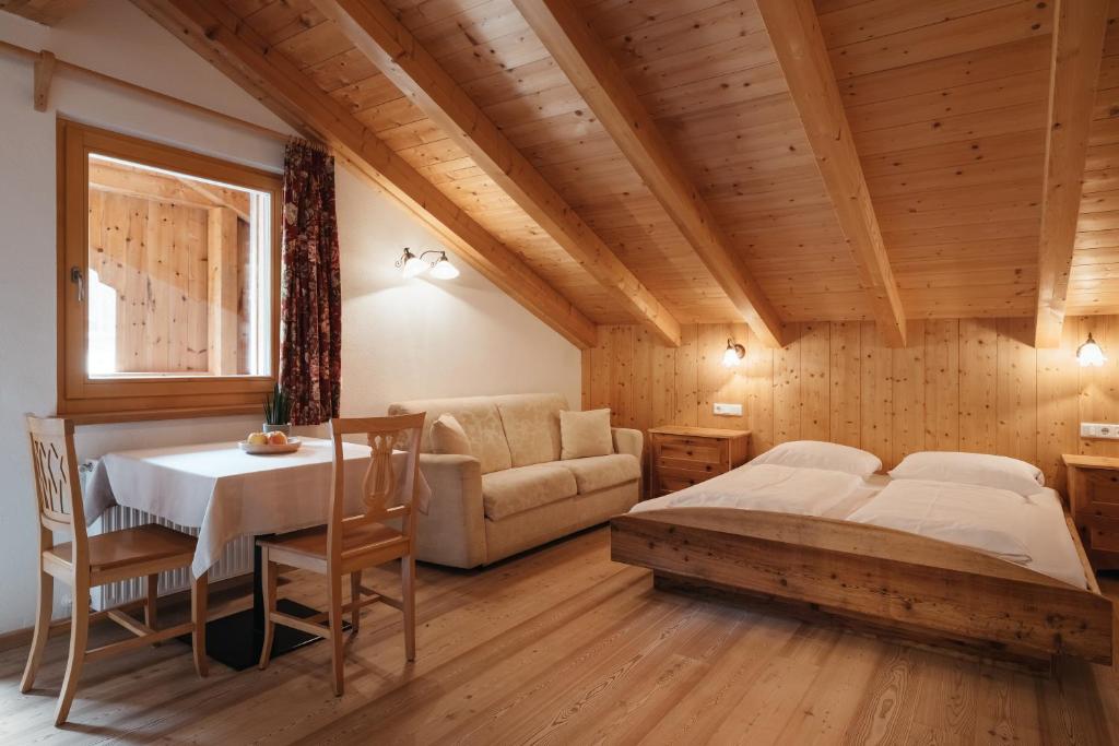 a bedroom with a bed and a table and a couch at Garni Ciasa Urban in Badia