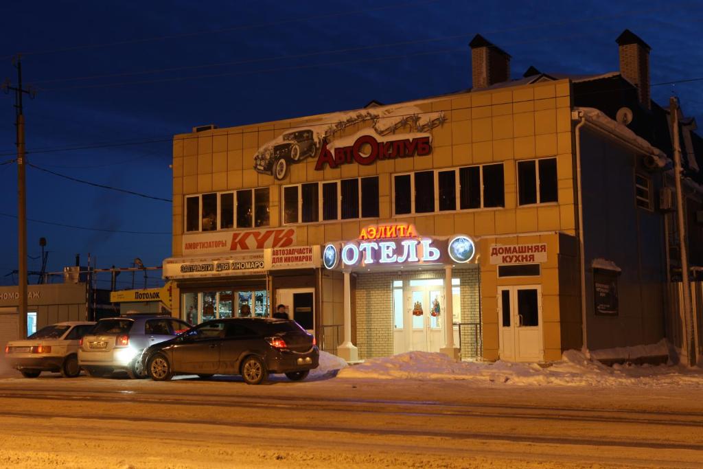 two cars parked in front of a building at night at Aelita Hotel in Volgodonsk