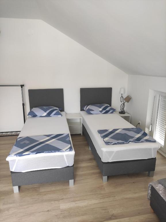two twin beds in a room with wooden floors at Apartments Markovi Konaci in Trebinje