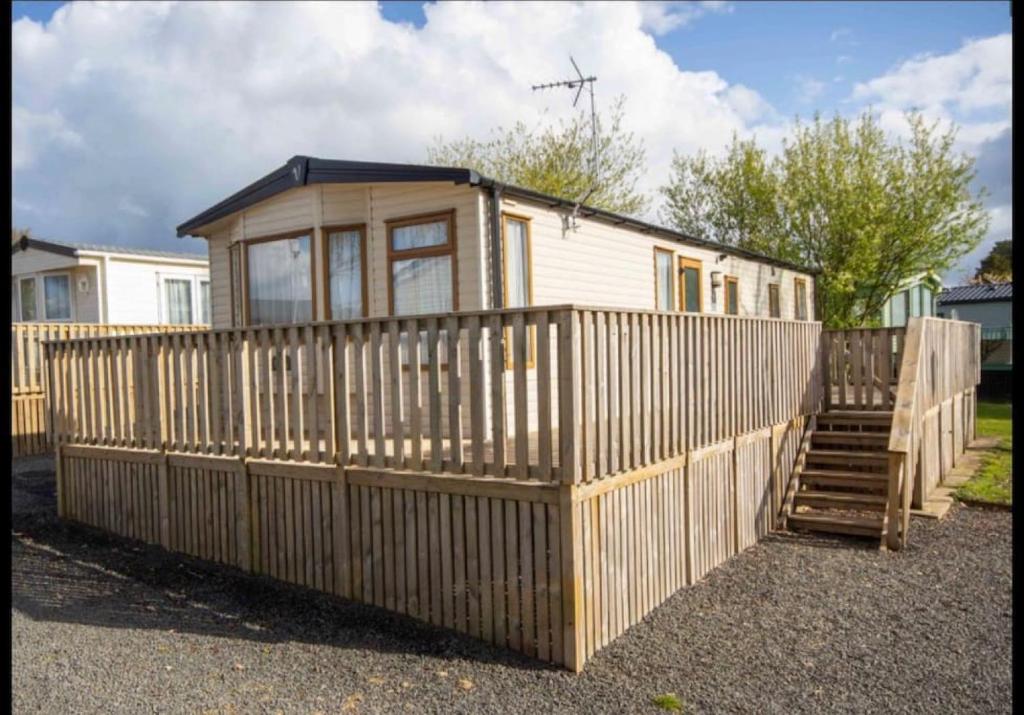 a tiny house with a wooden fence and stairs at Two Bedroom Caravan at Lilliarsedge in Jedburgh