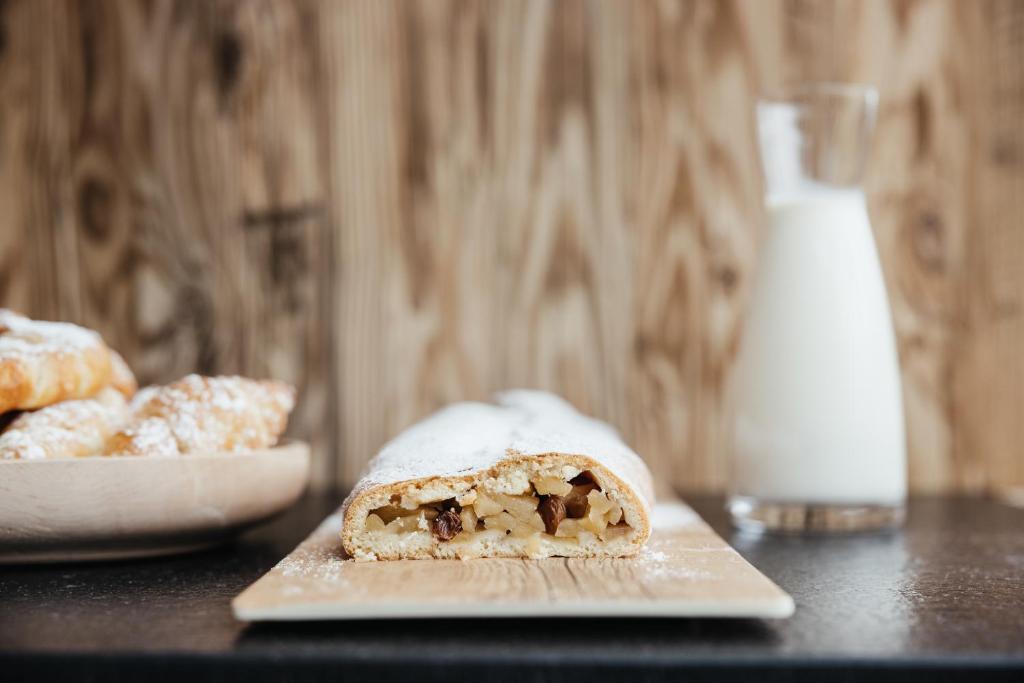 a pastry on a cutting board with a glass of milk at Garni Ciasa Urban in Badia