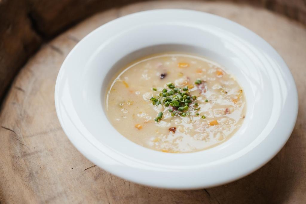 a white bowl of soup on a wooden table at Garni Ciasa Urban in Badia