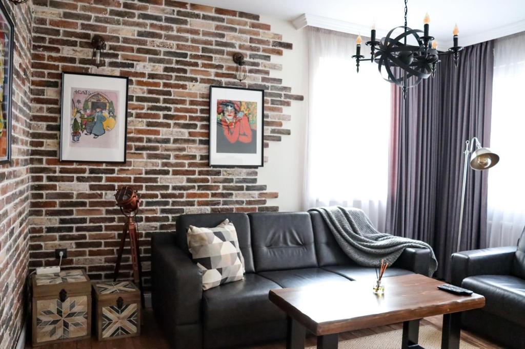 ein Wohnzimmer mit einer Backsteinwand und einer Couch in der Unterkunft Tsarevets Apartament-Veliko Tarnovo in Weliko Tarnowo