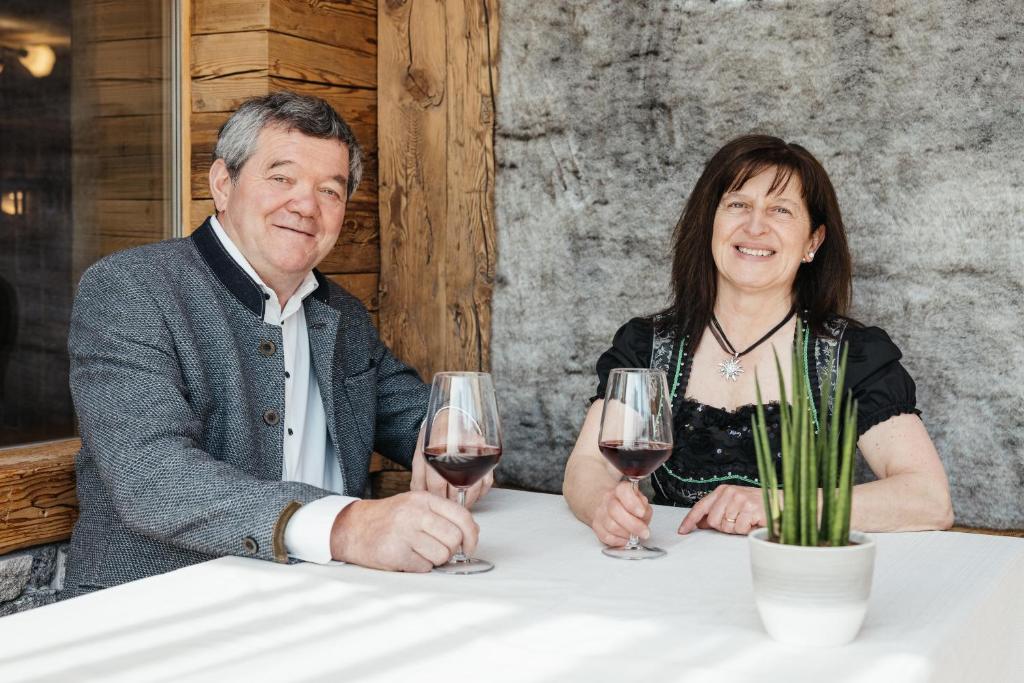 a man and woman sitting at a table with glasses of wine at Garni Ciasa Urban in Badia