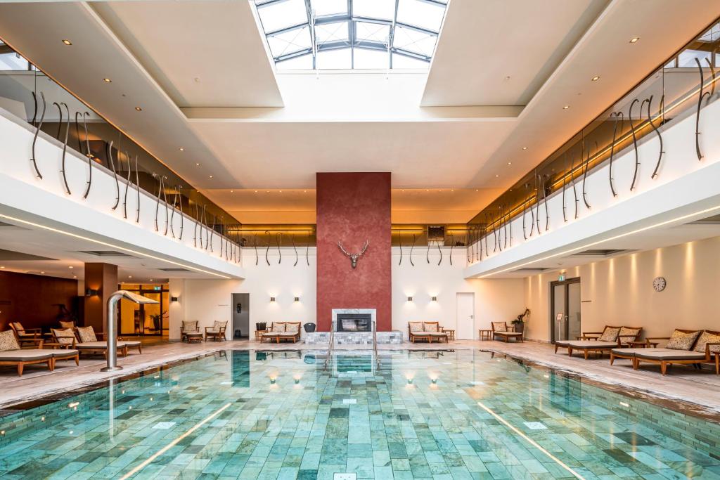 una piscina en el vestíbulo de un hotel con mesas y sillas en Wald & Schlosshotel Friedrichsruhe en Friedrichsruhe