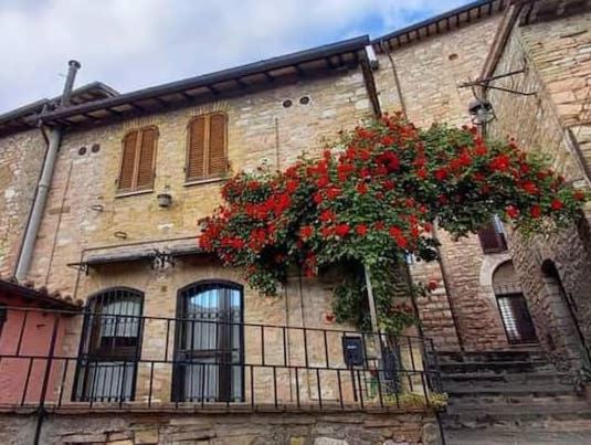 ein Gebäude mit einem Balkon mit roten Blumen darauf in der Unterkunft CASETTA delle ROSE in Assisi