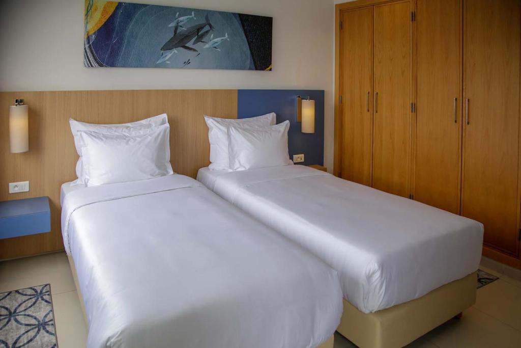 two beds in a hotel room with white sheets at Zephyr Agadir in Agadir