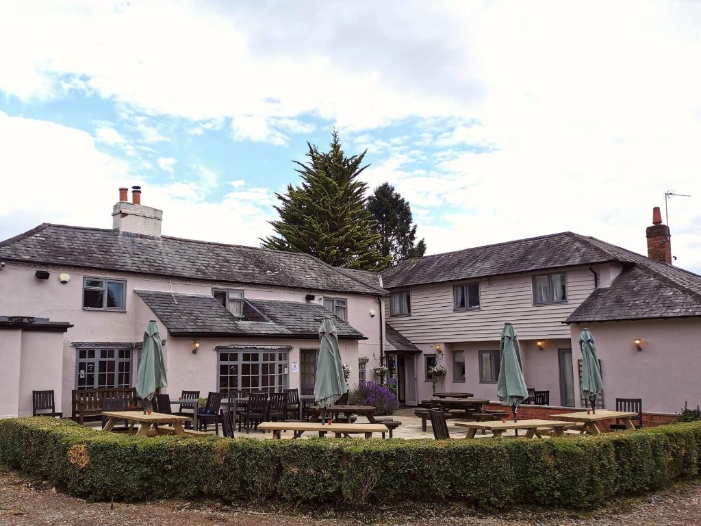 un grupo de mesas y sombrillas frente a un edificio en The Chilterns Fox, en Ibstone